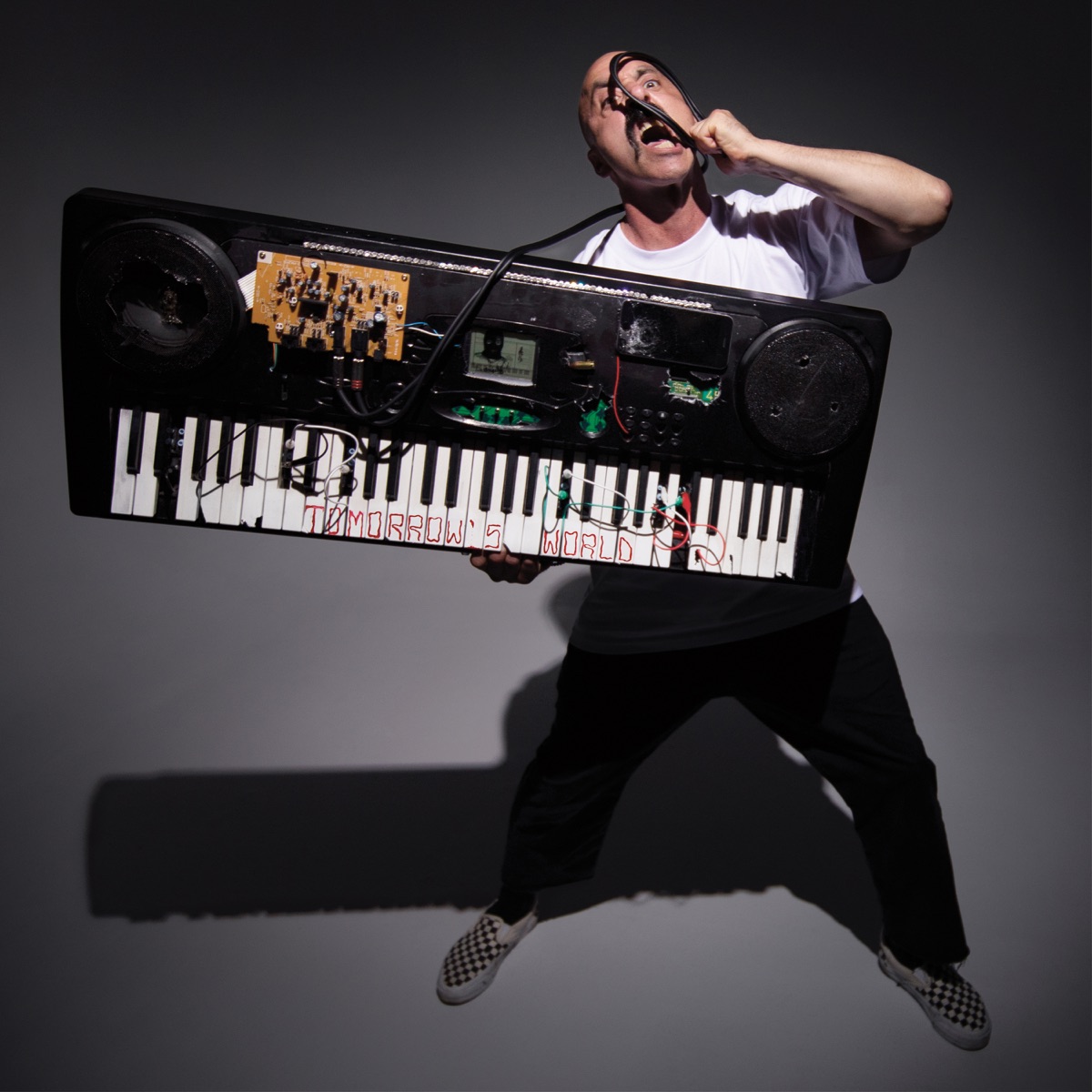 Tomorrow’s World album artwork: N8NOFACE holding a modified keyboard with exposed electronics and a cable loop raised to his face.